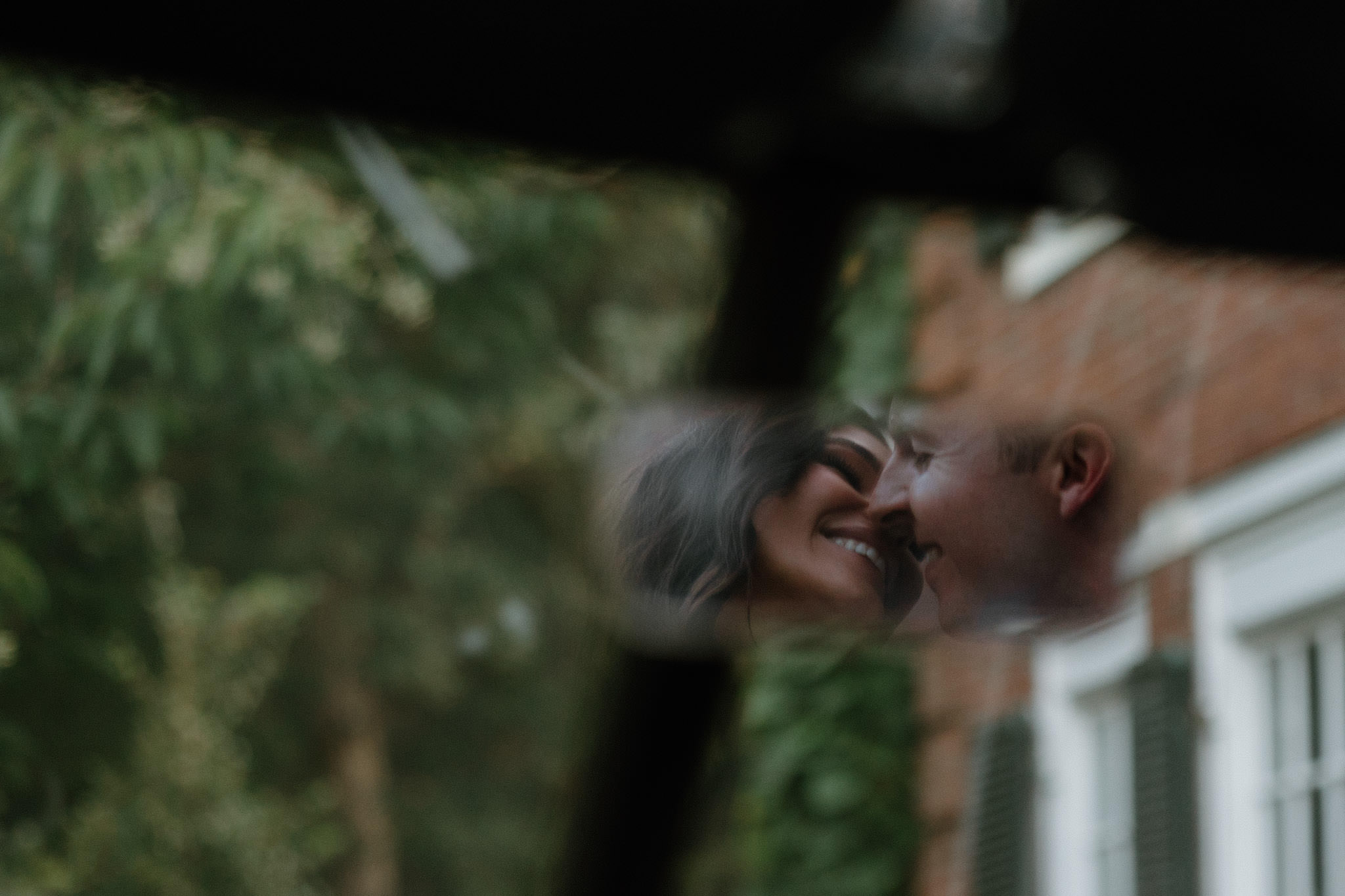 Couple smiles in rearview mirror of vintage car at Bradley Estate Engagement Photos