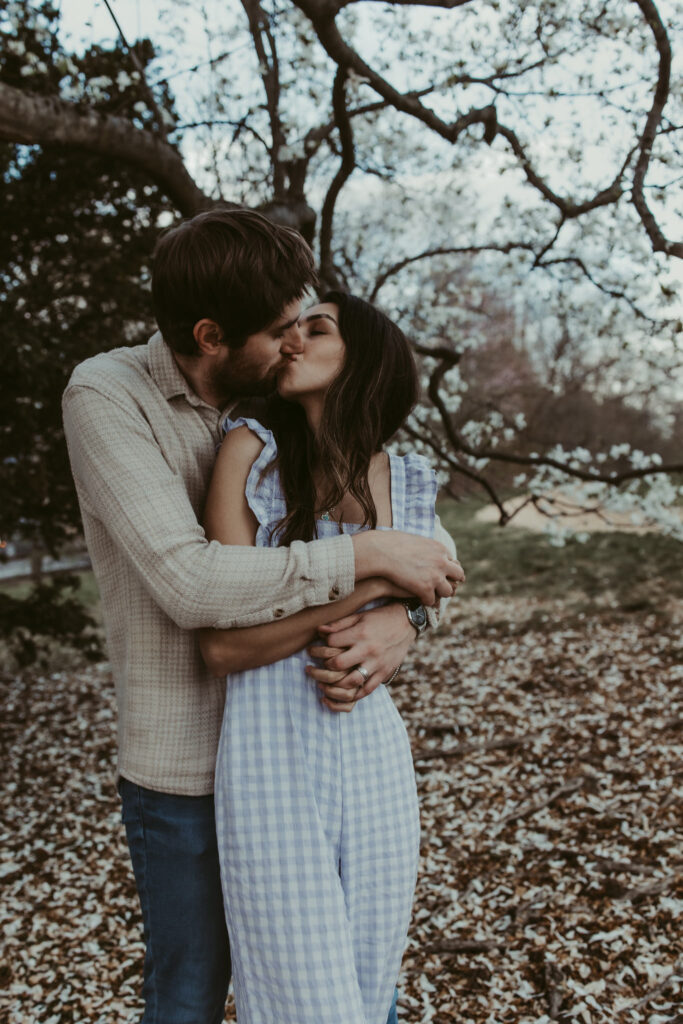 husband and wife kiss in the springtime after learning how to prepare for a photoshoot 