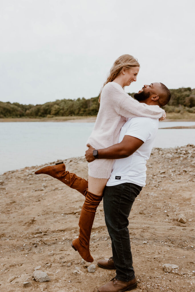 Husband picks up wife at their fun pregnancy announcement photoshoot. 