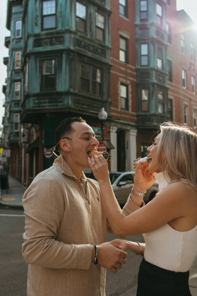 Boston couple shares cannoli outside of Bova's Bakery in Boston North End Engagement Photo Session 