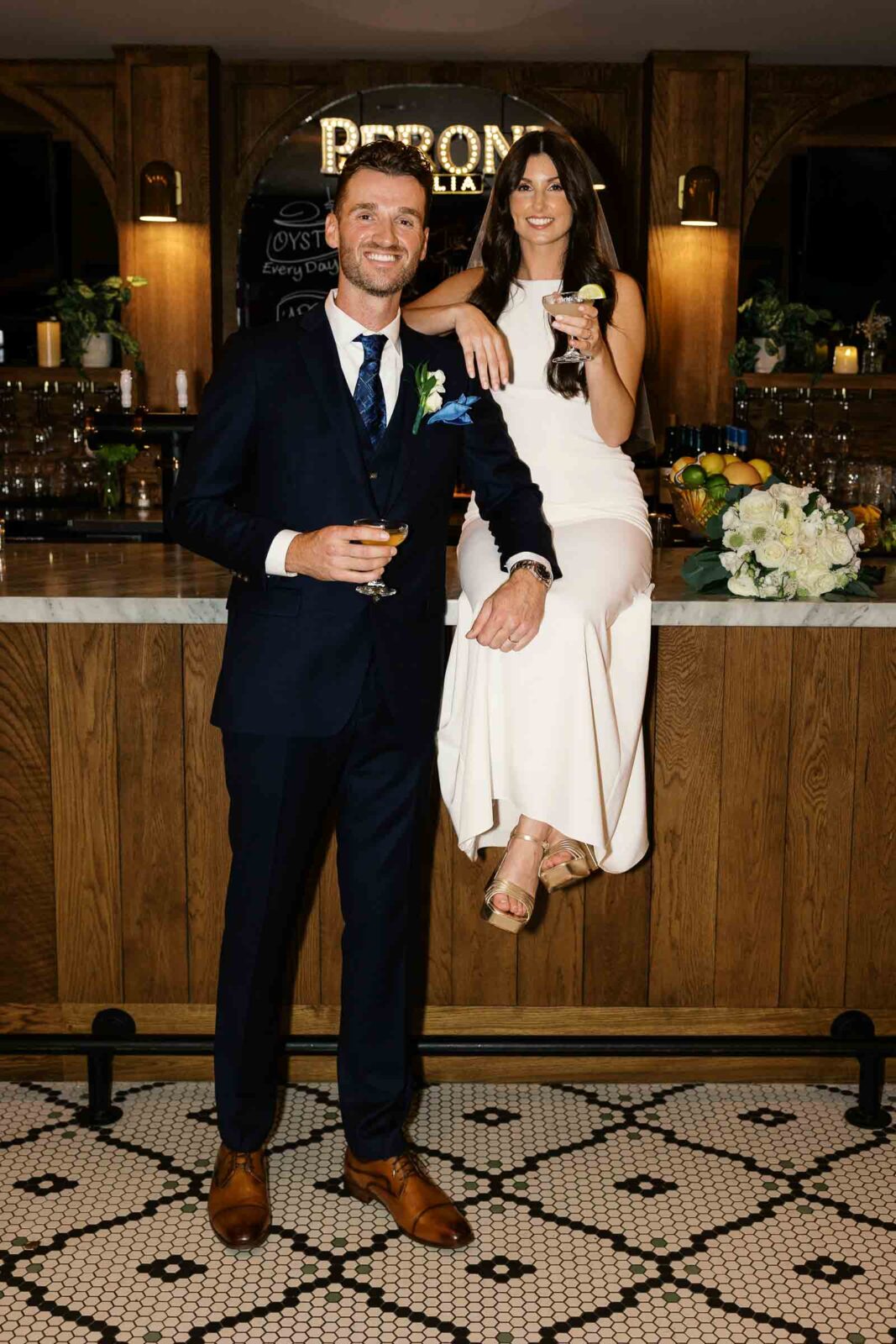 Bride and groom pose on the bar at Madre Osteria