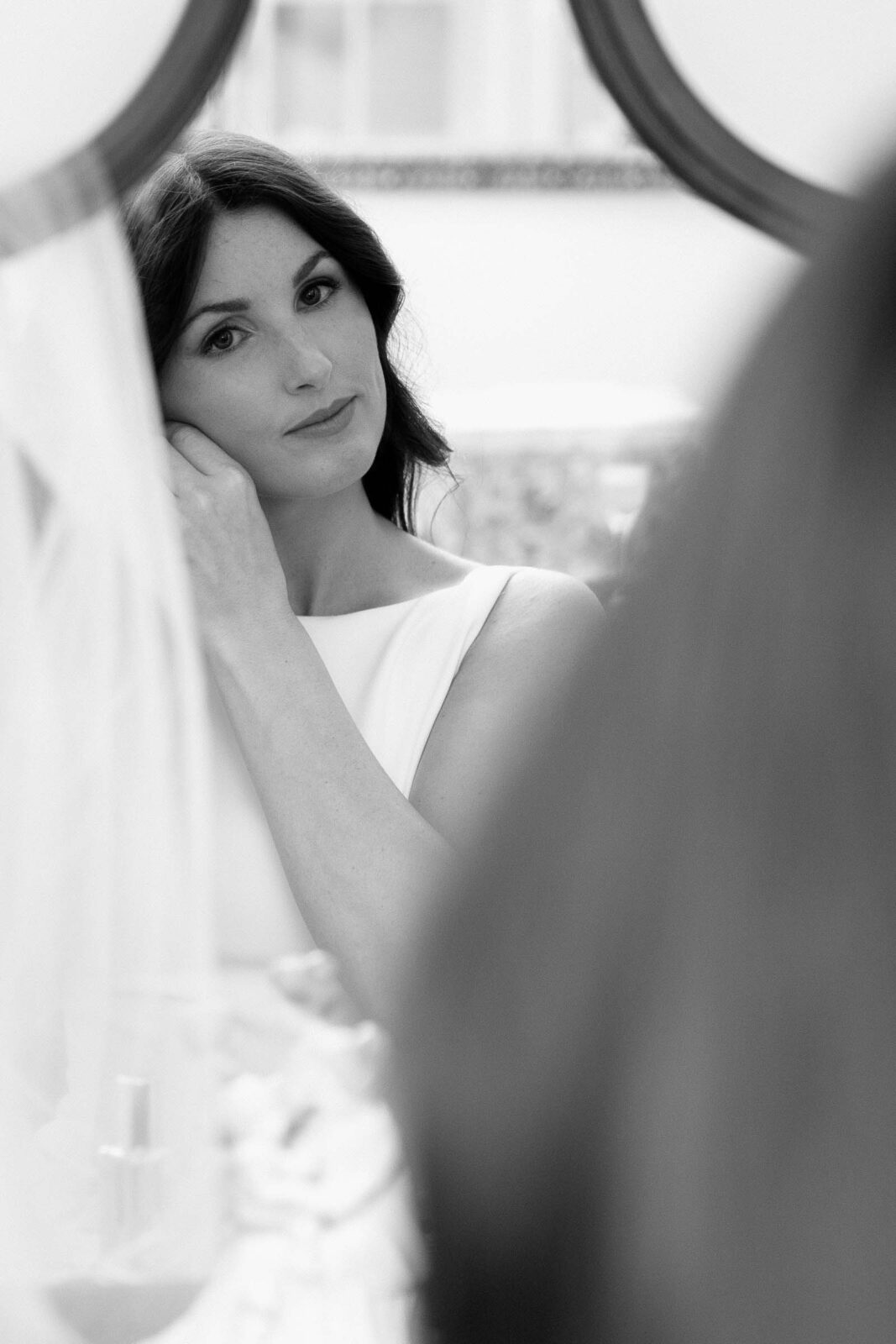 Bride fixes her earring while looking in mirror