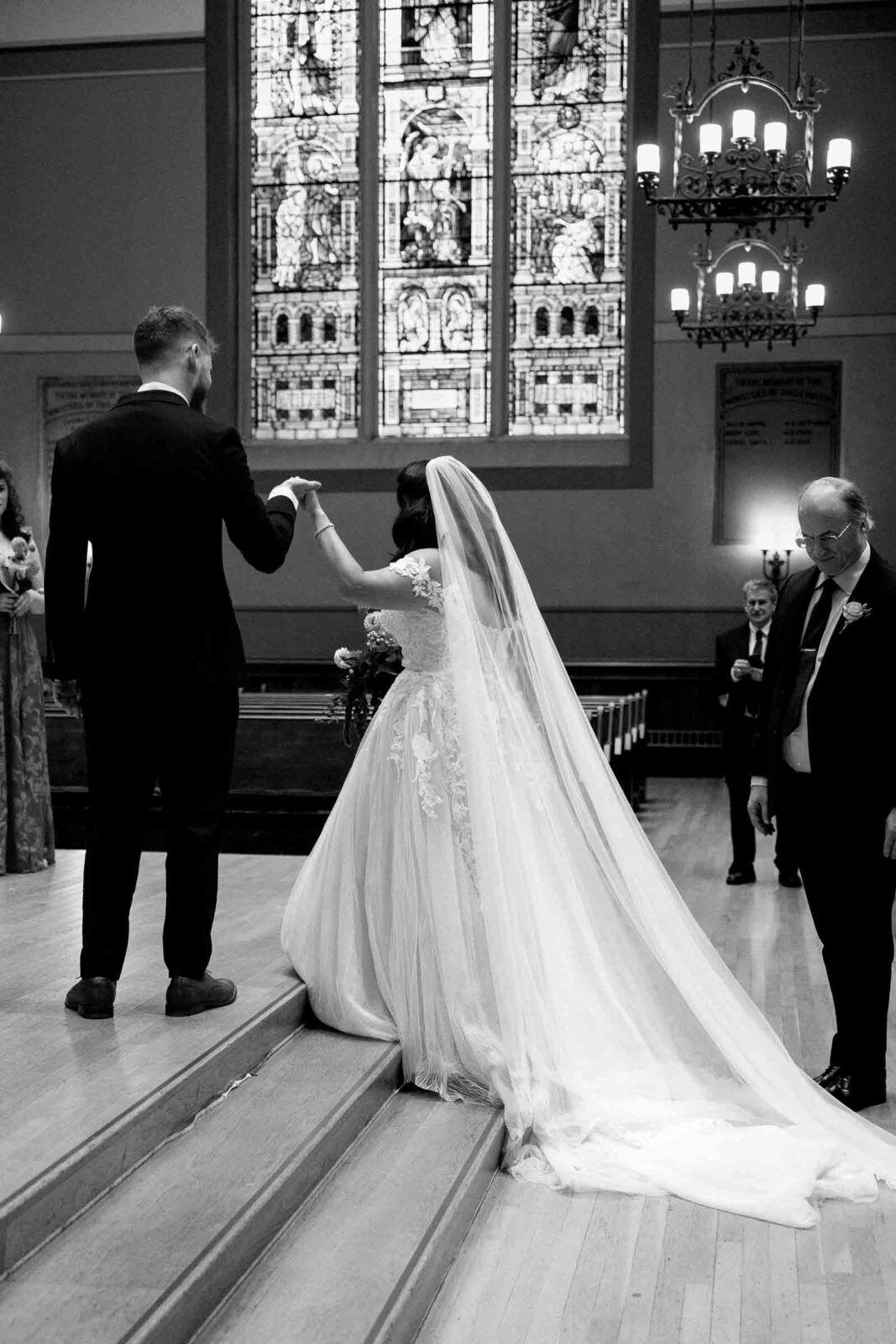 groom helps bride up the stairs at church wedding - umass club wedding boston MA